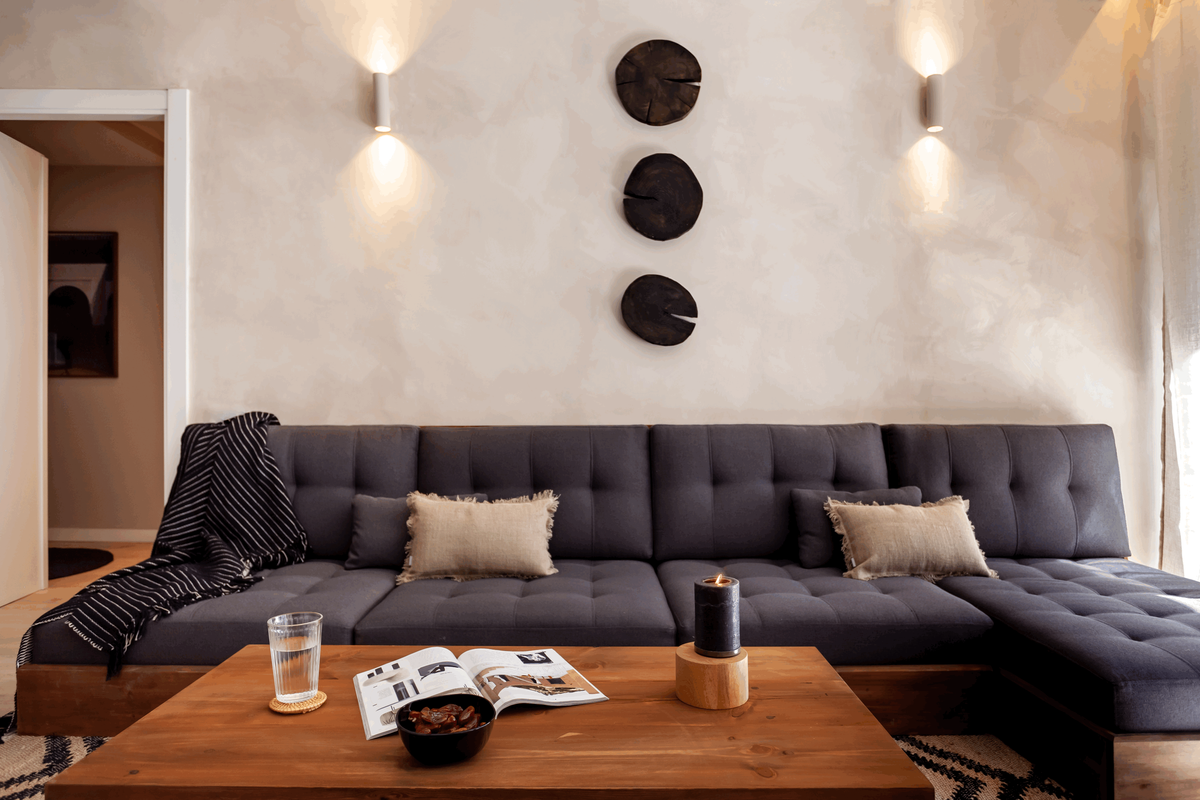 a living room with a couch and a coffee table. Beige lime wash wall paint, wall paint effect beige, big sofa, organic interior trend. Architectural digest, Elle decoration, Vt wonen, Noelle Baartmans, de Huismuts, interieur designer, Aptó interiors