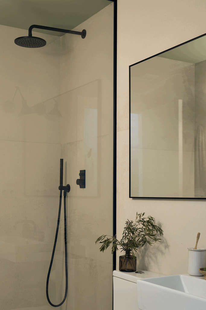 a bathroom with a shower, sink and mirror. Minimalist Bathroom, mirror with thin black frame. Bathroom decoration chique. Shower glass with thin black frame. Interior staging. Home staging by Aptó interiors in Barcelona and Amsterdam