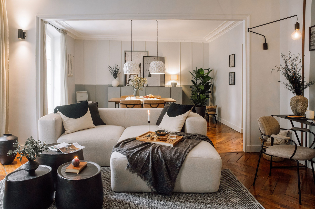 a living room with a couch and a coffee table. Parisian home design, Interior decorator. Big white couch, cozy living room, wall decoration, office set up, round coffee table. candles and magazines interior design. Noelle Baartmans, Aptó interiors